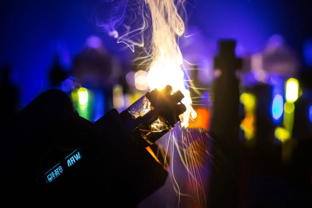 黑暗背景上電子煙的煙雲和蒸汽液體瓶光的效果