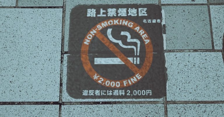 Close-up of a non-smoking area sign on a city sidewalk, highlighting a ¥2,000 fine warning.